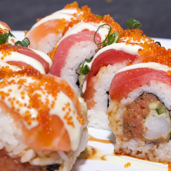Close-up of Akita Sushi Gourmet's sushi rolls with salmon, tuna, roe, and creamy sauce.