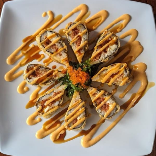 Eight pieces of Akita Sushi's deep-fried sushi rolls, drizzled with sauce and garnished with roe and greens.