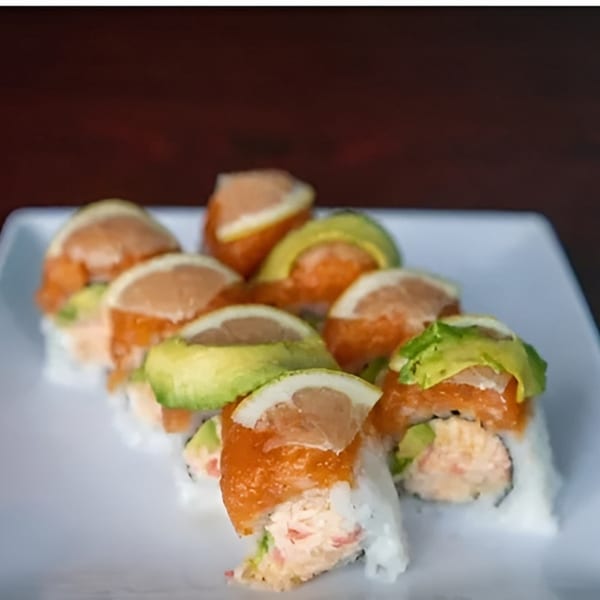 Akita Sushi Gourmet's sushi rolls topped with salmon, avocado, and grapefruit slices on a white plate.