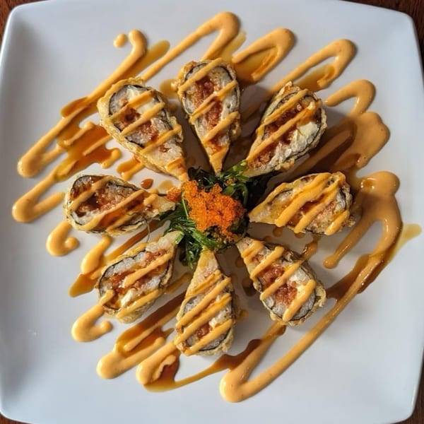 Eight pieces of Akita Sushi's fried sushi rolls with spicy mayo and eel sauce, garnished with tobiko.