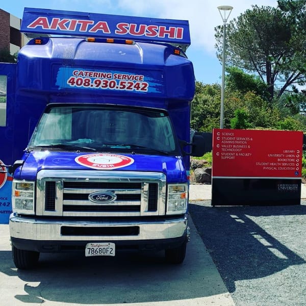Akita Sushi catering truck parked next to a California State University directional sign.
