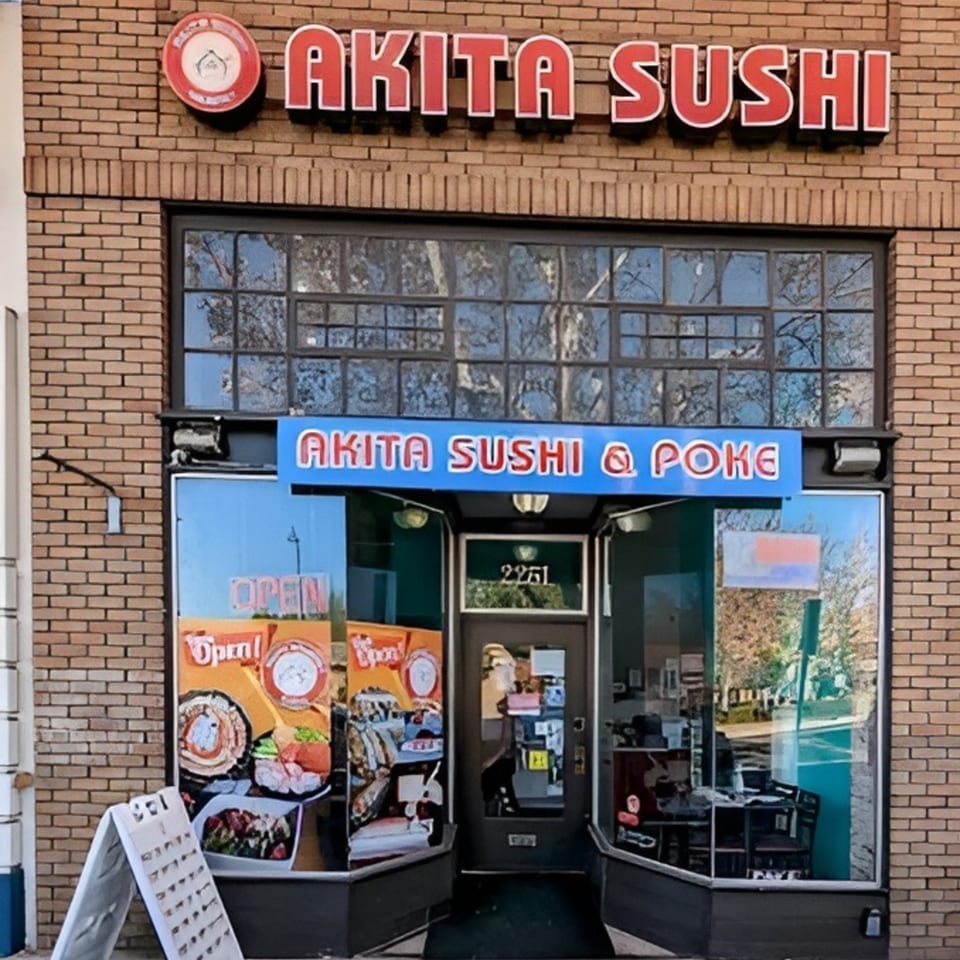Exterior of Akita Sushi restaurant with a brick facade, large windows, and prominent signage.