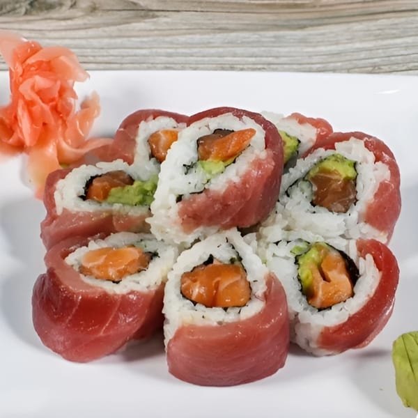 Akita Sushi's tuna and salmon sushi rolls with avocado, rice, and pickled ginger on a white plate.